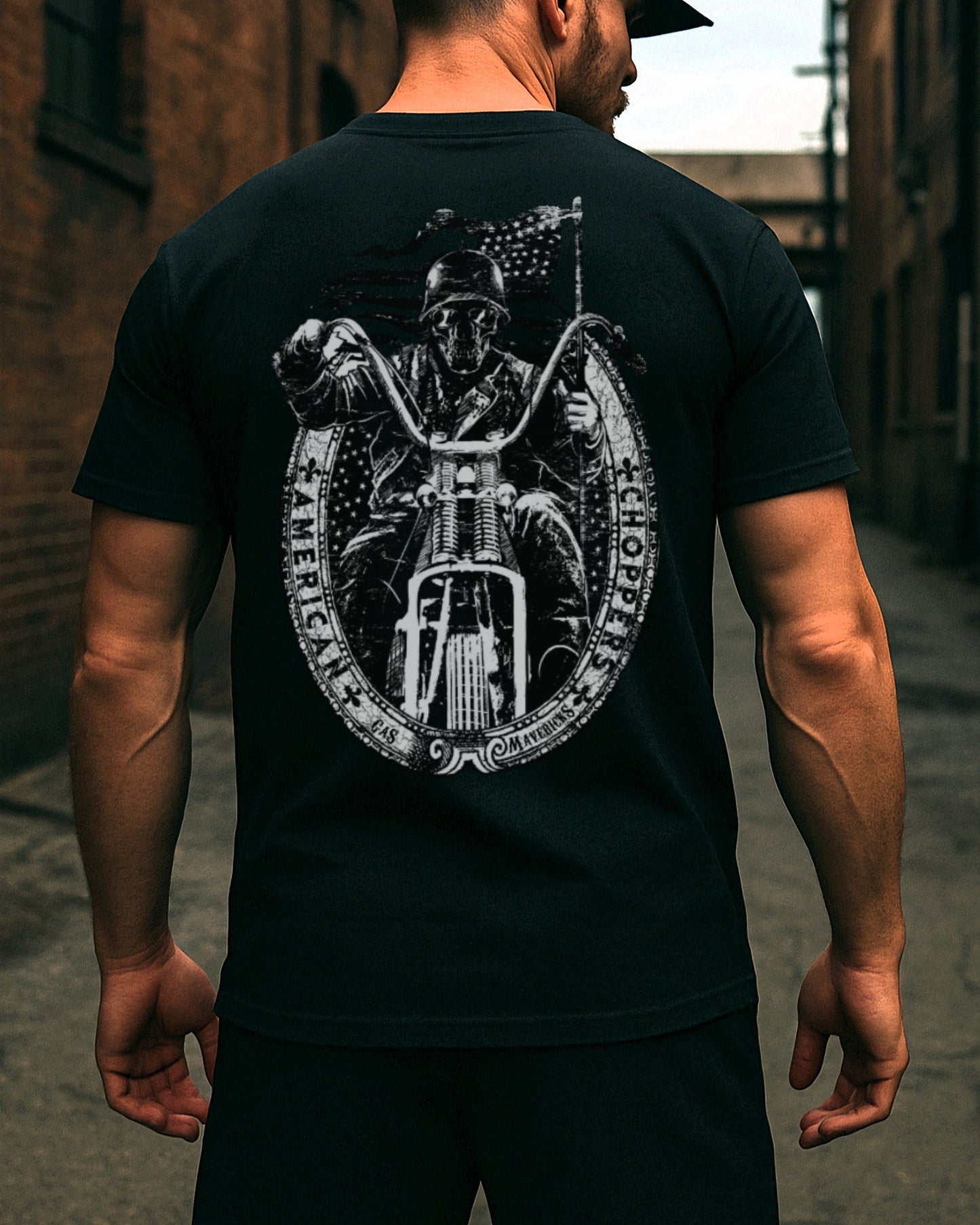Back view of a muscular man wearing a black Gas Mavericks T-shirt with a detailed backprint of a skull-faced biker on a chopper and an American flag in the background.
