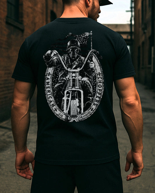 Back view of a muscular man wearing a black Gas Mavericks T-shirt with a detailed backprint of a skull-faced biker on a chopper and an American flag in the background.