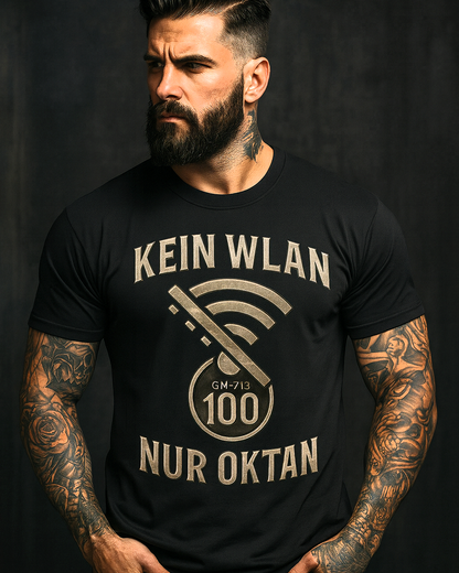 Tattooed man wearing black Gas Mavericks T-shirt with bold slogan Kein WLAN Nur Oktan, standing in dark studio setting
